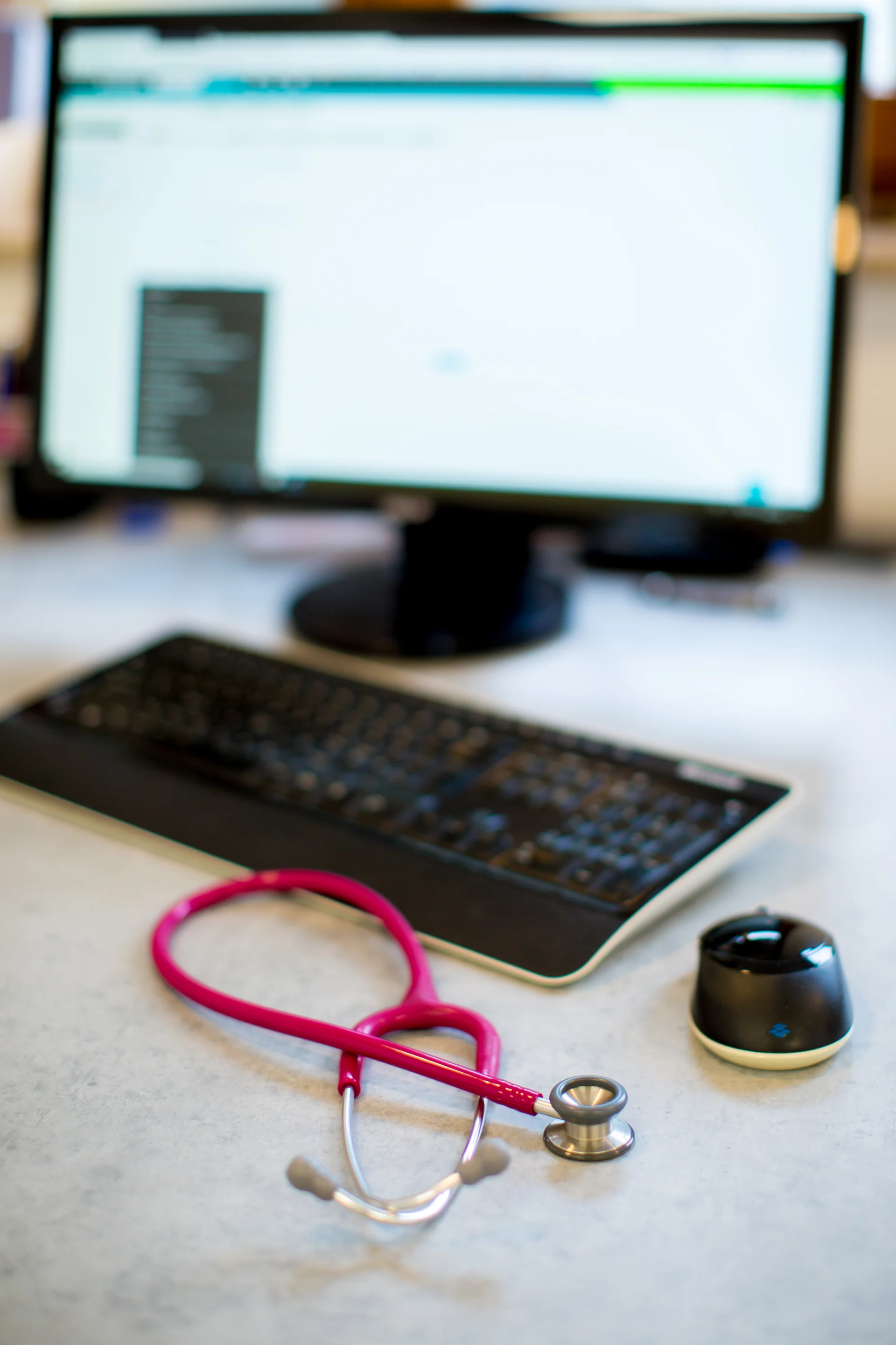 Bildschirm, Tastatur und Stethoskop davor liegend