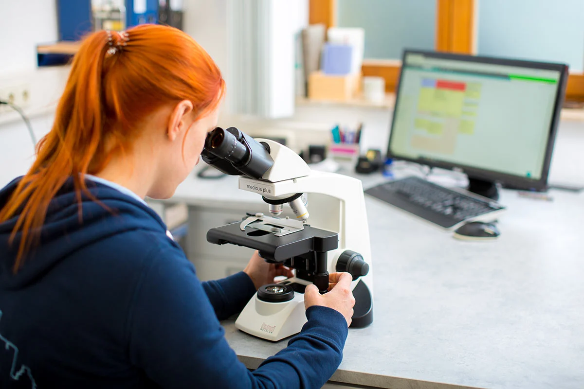 Tierärztin untersucht etwas unter einem Mikroskop.